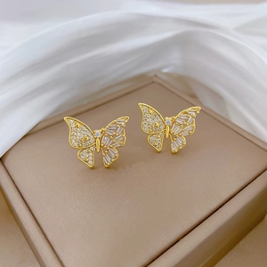 Détail de boucles d'oreilles papillon dorées avec micro-sertissage de cristaux brillants