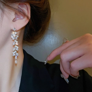 Elegant silver tassel earrings with zircon leaves worn by a model in a profile view