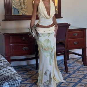 Detail of the halter neck top and floral long skirt with slit in a soft yellow color