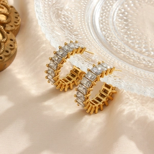 Gros plan sur les boucles d'oreilles dorées 18K en C avec zircons rectangulaires