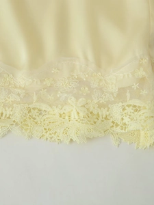 Détail de l'ourlet en satin jaune avec dentelle fine sur cet ensemble de nuit pour femme