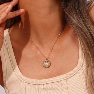 Gros plan d'un collier pendentif doré avec cœur blanc et texture rayon de soleil