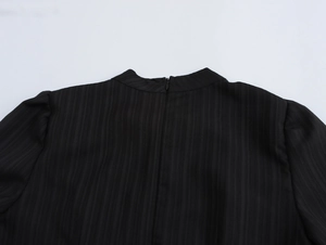 Λεπτομέρεια της πλάτης του μαύρου φορέματος με κάθετη υφή και κρυφό φερμουάρ στο κέντρο