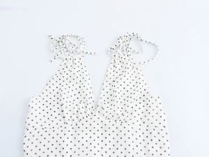 Gros plan sur une robe à pois blancs avec fines bretelles et décolleté plongeant en V