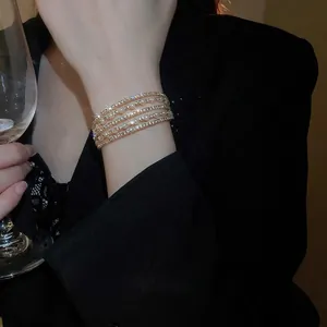 Elegant multi-layer gold bracelet with white pearls and sparkling pavé diamonds on wrist