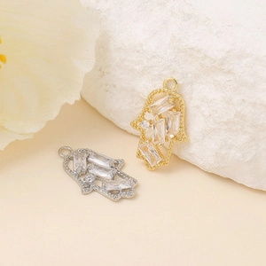 Macro shot of gold and silver Hamsa hand pendants inlaid with clear cubic zirconia