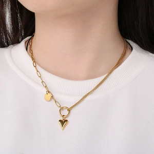 Detail of gold heart pendant necklace with paperclip and cuban link chain worn by model