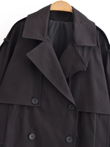 Detail of double-breasted black trench coat with large lapels and premium buttons