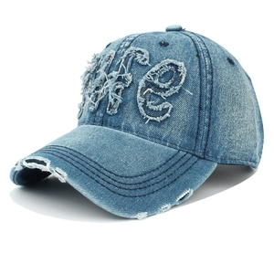 Détail d'une casquette en denim vieilli avec broderie LIFE et bords effilochés