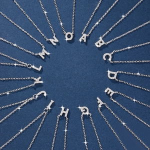 Close-up of sparkling crystal-encrusted 925 silver alphabet pendants on dark background
