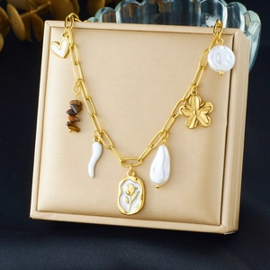 Detail of gold bracelet with tiger eye stone, heart pendant and pearl on jewelry box