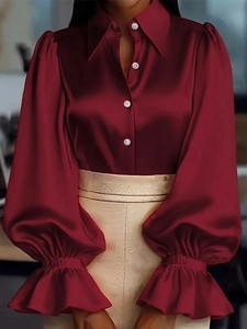 Dettaglio camicia in raso rosso vino con eleganti maniche a sbuffo e tessuto lucido