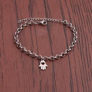 Polished stainless steel bracelet with Hamsa hand and heart pendant on textured background
