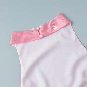 Detail of neckline with floral print trim and decorative pearl buttons on satin vest