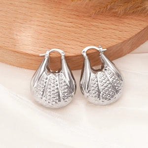 Détail macro de boucles d'oreilles argentées avec texture en treillis sur bois
