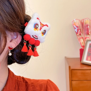 Detail of plush dancing lion hair clip with embroidery and red tassels on model