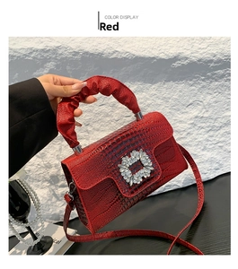 Detail of red croc-effect bag with crystal buckle and ruched handle texture