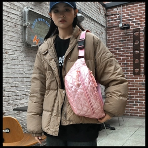 Detailed close-up of pink quilted puffer belt bag with a black buckle and woven zipper pull