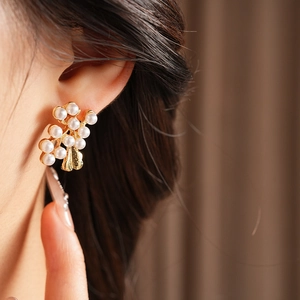 Close-up of vintage flower pearl earrings on model with golden metal leaf detail