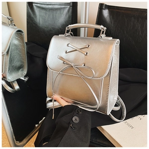 Detail of silver metallic backpack featuring a stylish bow and criss-cross ribbon design
