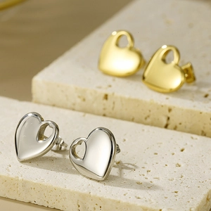 Detailed macro shot of 18K gold and silver heart earrings with stylish hollow cutout