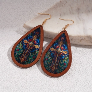 Detail of wooden teardrop earrings with stained glass cross pattern and gold hooks