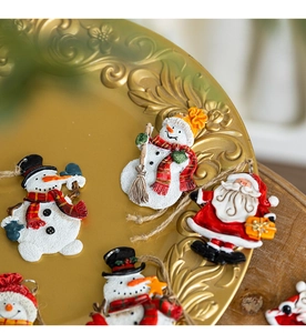 Close-up of vintage resin snowman and Santa hanging ornaments on a golden tray