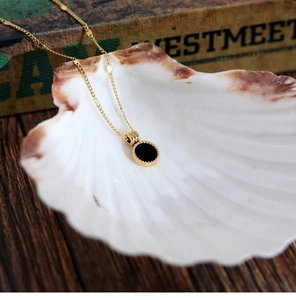Detail of 18K gold-plated stainless steel necklace with black round shell pendant inlay
