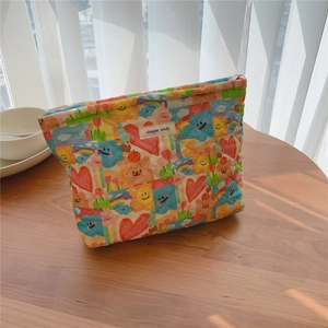 Macro detail of quilted makeup bag with teddy bear and floral prints on a wood desk