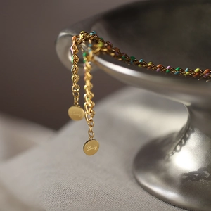 Gold-plated chain bracelet with colorful enamel accents and Lucky coin charms