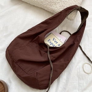 Detail view of brown corduroy strap and pleated nylon fabric on a large tote bag