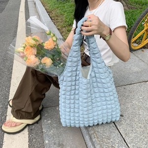 Light blue bubble texture shoulder bag carried by a model in a natural outdoor setting