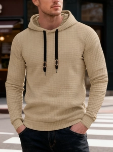 Macro detail of men's khaki waffle knit hoodie fabric with black contrast drawstrings