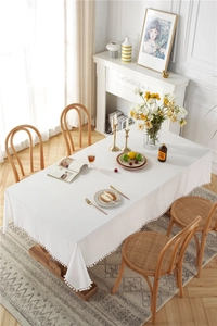 Detail of white cotton tablecloth edge featuring soft decorative pom-pom fringe trim