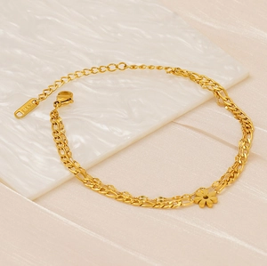 Detail of 18K gold Figaro chain bracelet featuring a double layer design and daisy charm