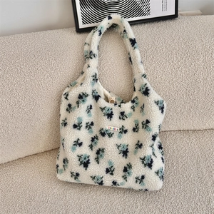 Detail of floral plush tote bag with lamb wool texture resting on a cozy sofa