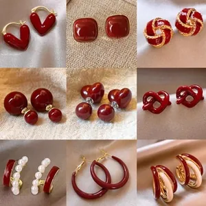 Vue macro de boucles d'oreilles vintage en émail rouge vin avec détails dorés et perles