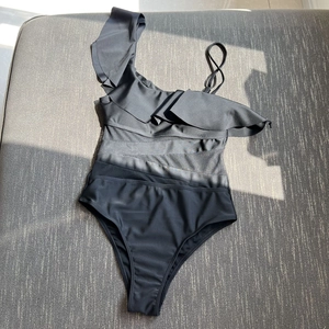 Detailansicht des schwarzen One-Shoulder-Badeanzugs mit Mesh-Einsatz und Rüschen