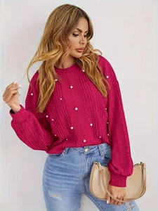 Gros plan du pull rose à manches bouffantes avec des ornements en perles blanches
