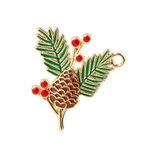 Macro detail of enamel pine cone charm with green leaves and red berries for DIY jewelry