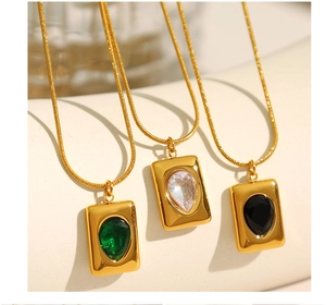 Macro shot of 18K gold plated necklaces featuring emerald and crystal pendants
