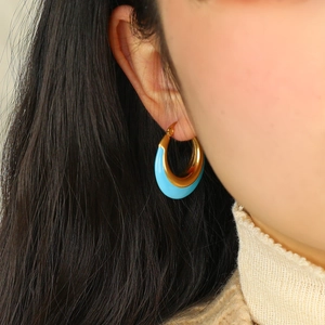 Boucles d'oreilles créoles en C bleu turquoise et doré portées par un mannequin