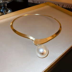 Detail of gold necklace with large white pearl pendant and floral accent on a tray