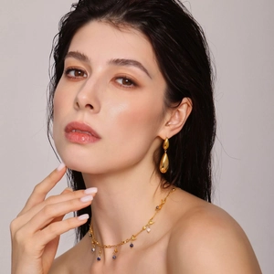 Minimalist gold teardrop earrings and beaded necklace jewelry set on female model