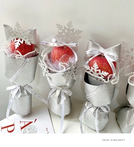 Detail of red Christmas apple gift wrap with silver glitter paper and pearl ribbon