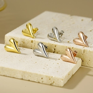 Three pairs of 3D heart stud earrings in gold, silver, and rose gold on stone pedestals