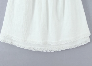 Close-up of white dress hem featuring delicate double-layer lace and eyelet embroidery