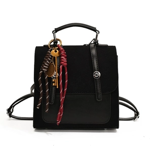 Mochila retro de cuero negro y ante con colgantes vintage sobre un fondo blanco limpio