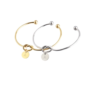 Detailed view of knot bangle with letter A charm in gold and silver stainless steel