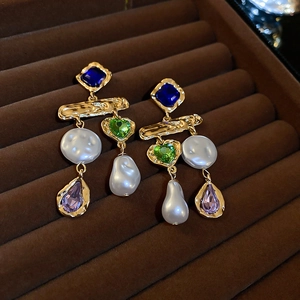 Nahaufnahme von Vintage-Ohrringen mit bunten Kristallen und Perlen auf Samttablett